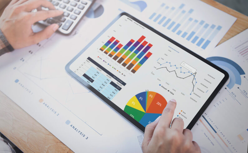 AboutIT-Sage-Intacct-is-a-powerful-financial-management Professional man using a tablet to review and analyze data, seated at a desk in a corporate environment.